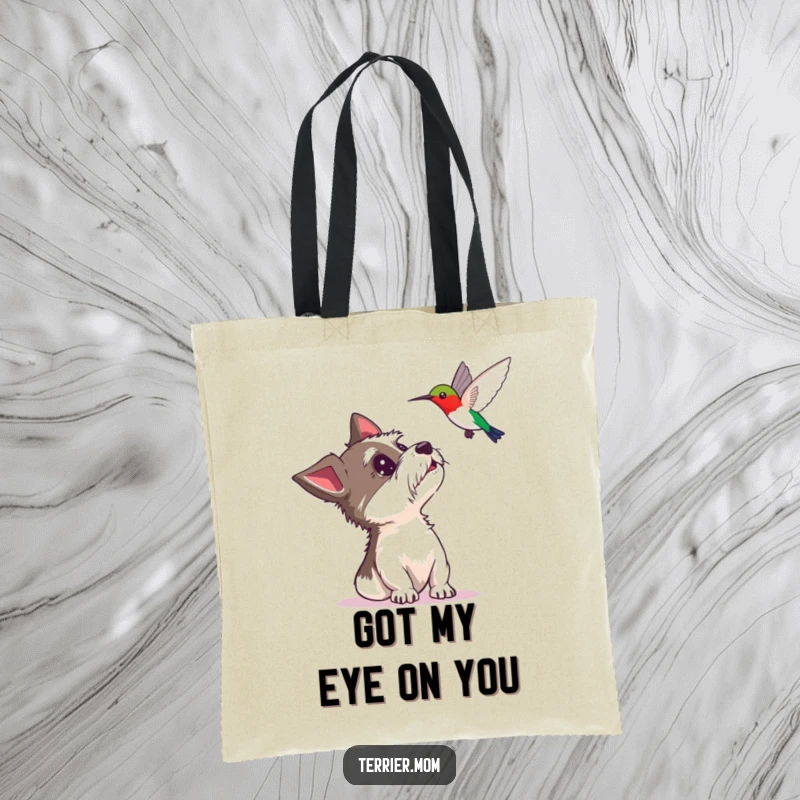 Funny tote bag showcasing a surprised terrier looking up at a hovering hummingbird, a stylish and humorous accessory for everyday use.